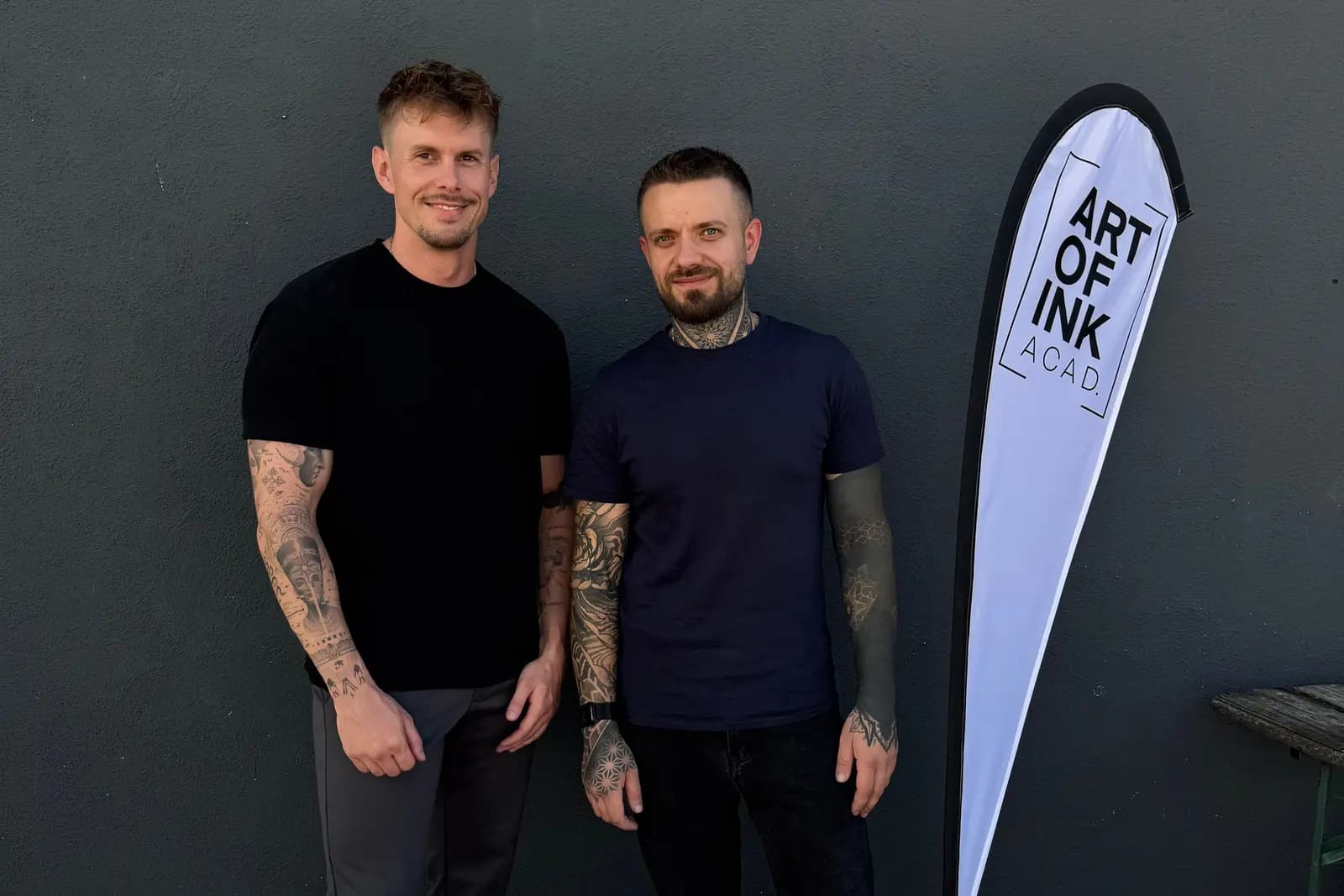 Philipp und Vitali, die Trainer der Art of Ink Academy, neben dem Art-of-Ink-Banner