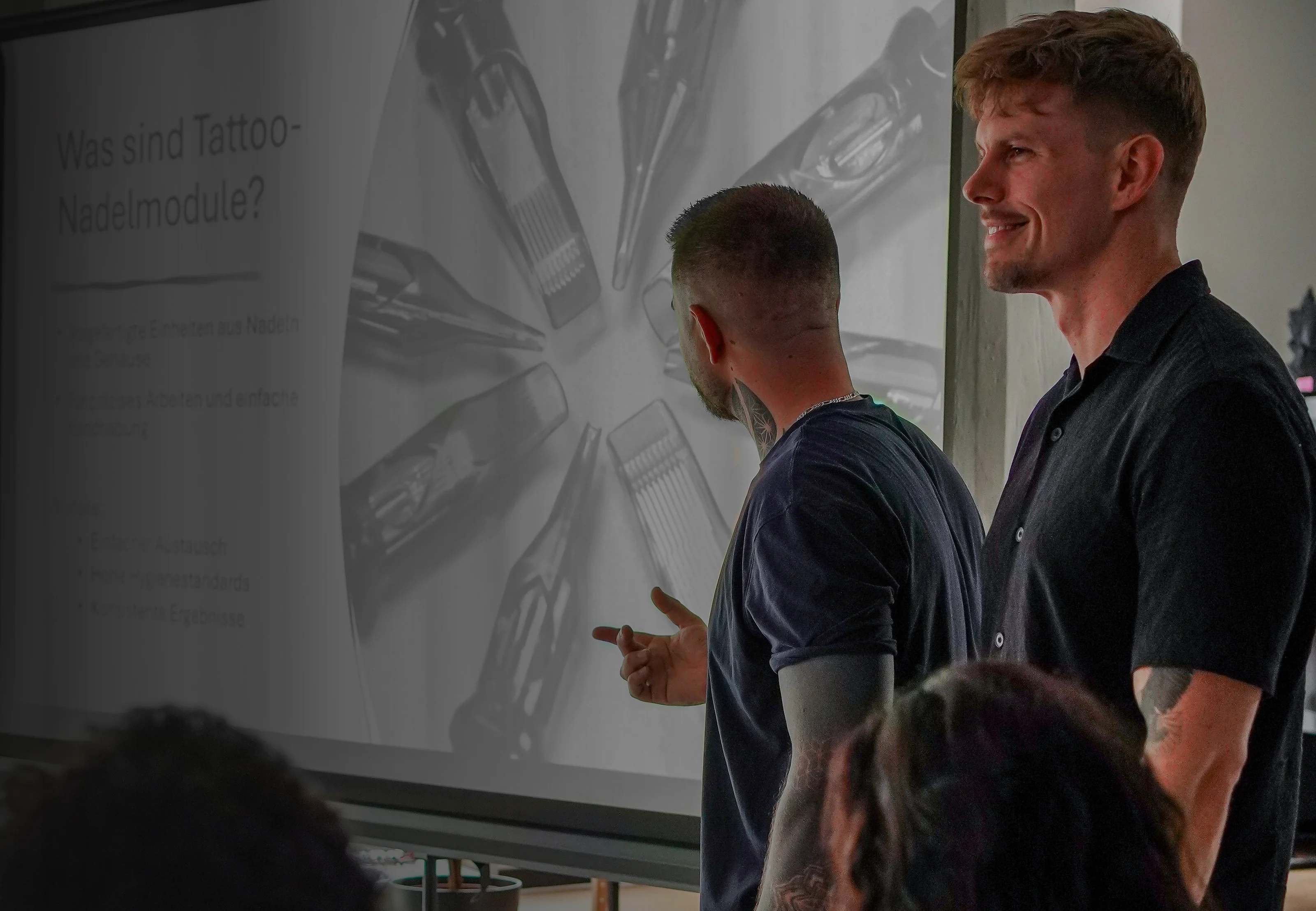 Die beiden Trainer der Art of Ink Academy erklären im Seminar Tattoo-Nadelmodule am Beamer